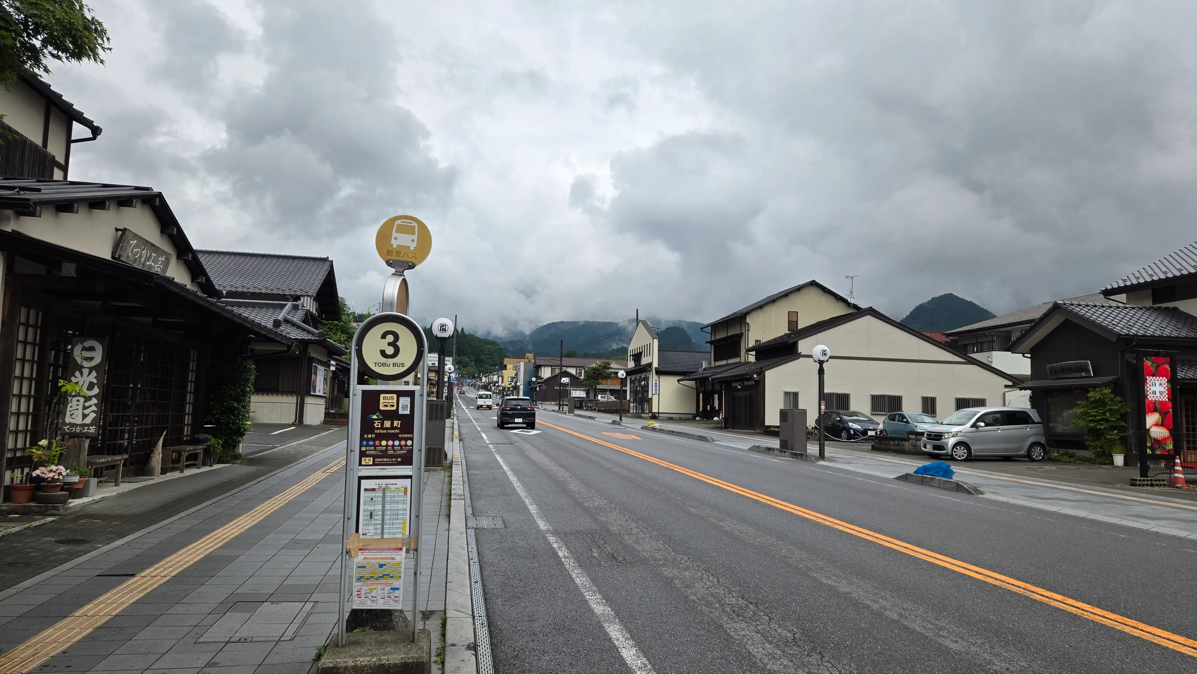 陰天的日光車站前廣場與巴士，以及通往山內的日光主街道，路邊是低矮的老店舖。