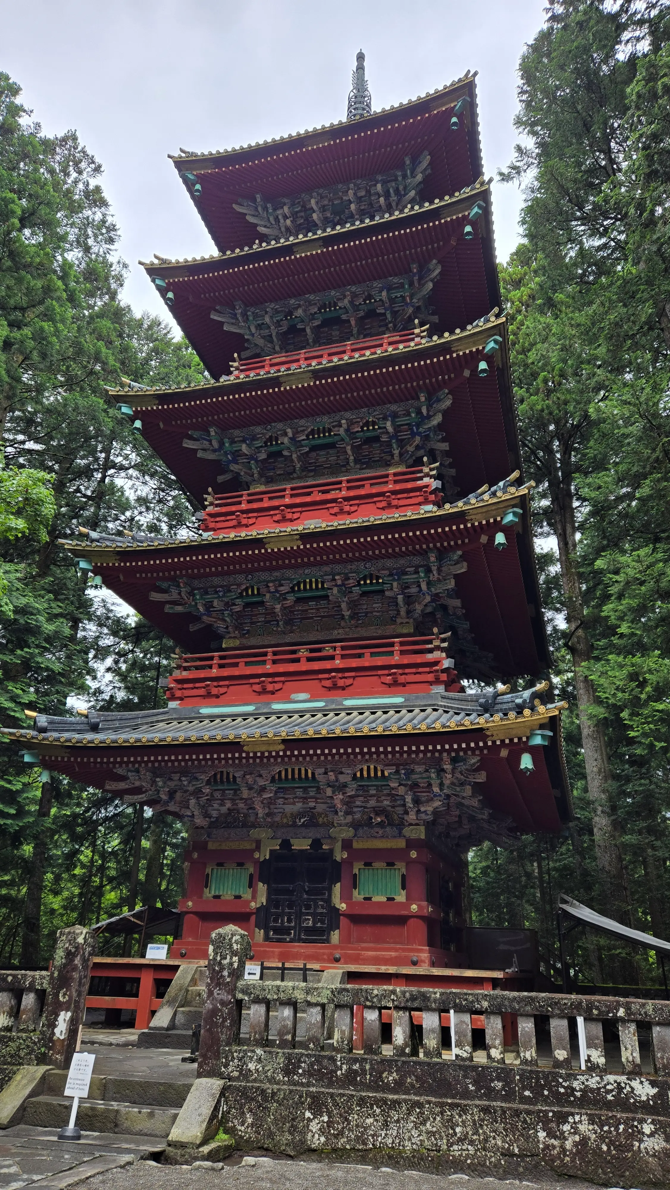 東照宮的五重塔，朱紅色的塔身層層疊上，隱在杉林之間。