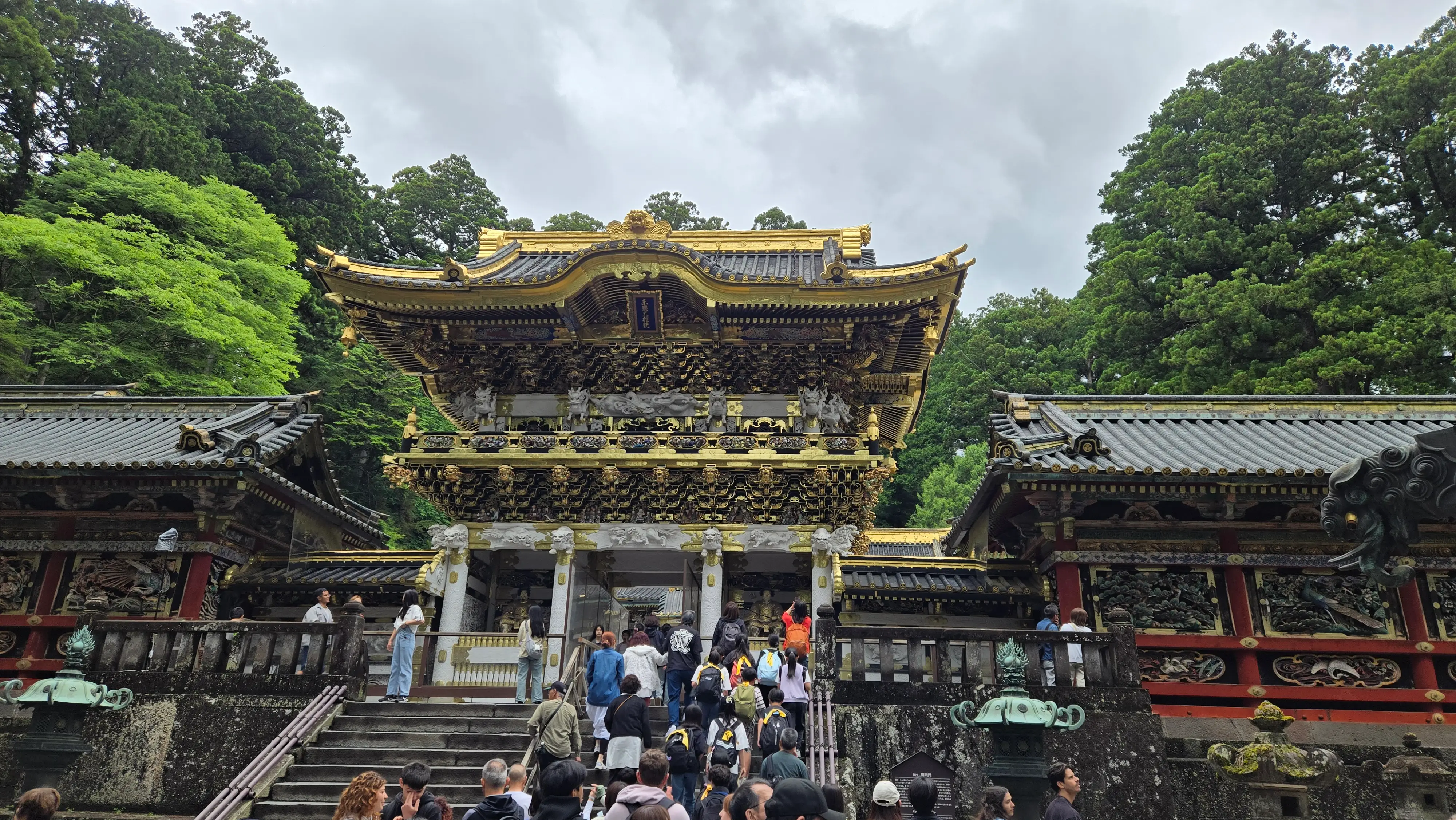 東照宮陽明門，金白相間的雕刻層層堆疊，門前是等著上階的人群。